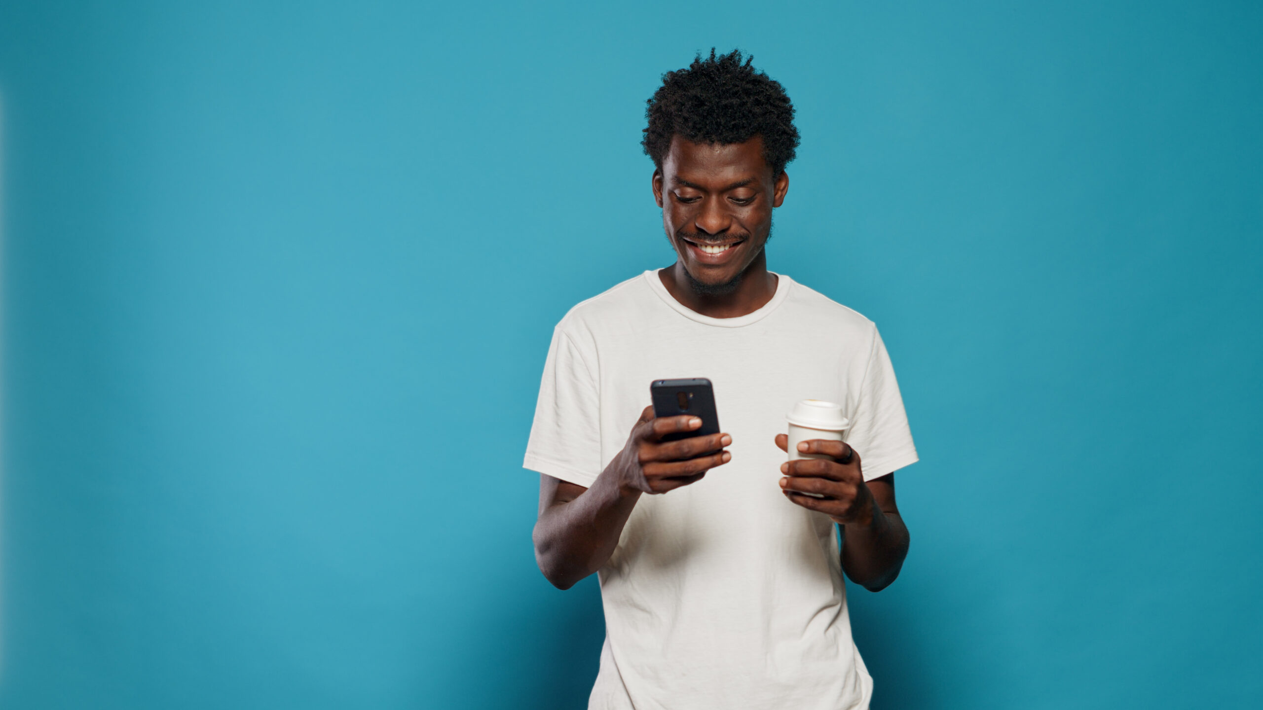 Portrait of modern person looking at display on smartphone. Cheerful man using mobile phone with touchscreen, feeling charismatic. Adult holding device with technology in studio.